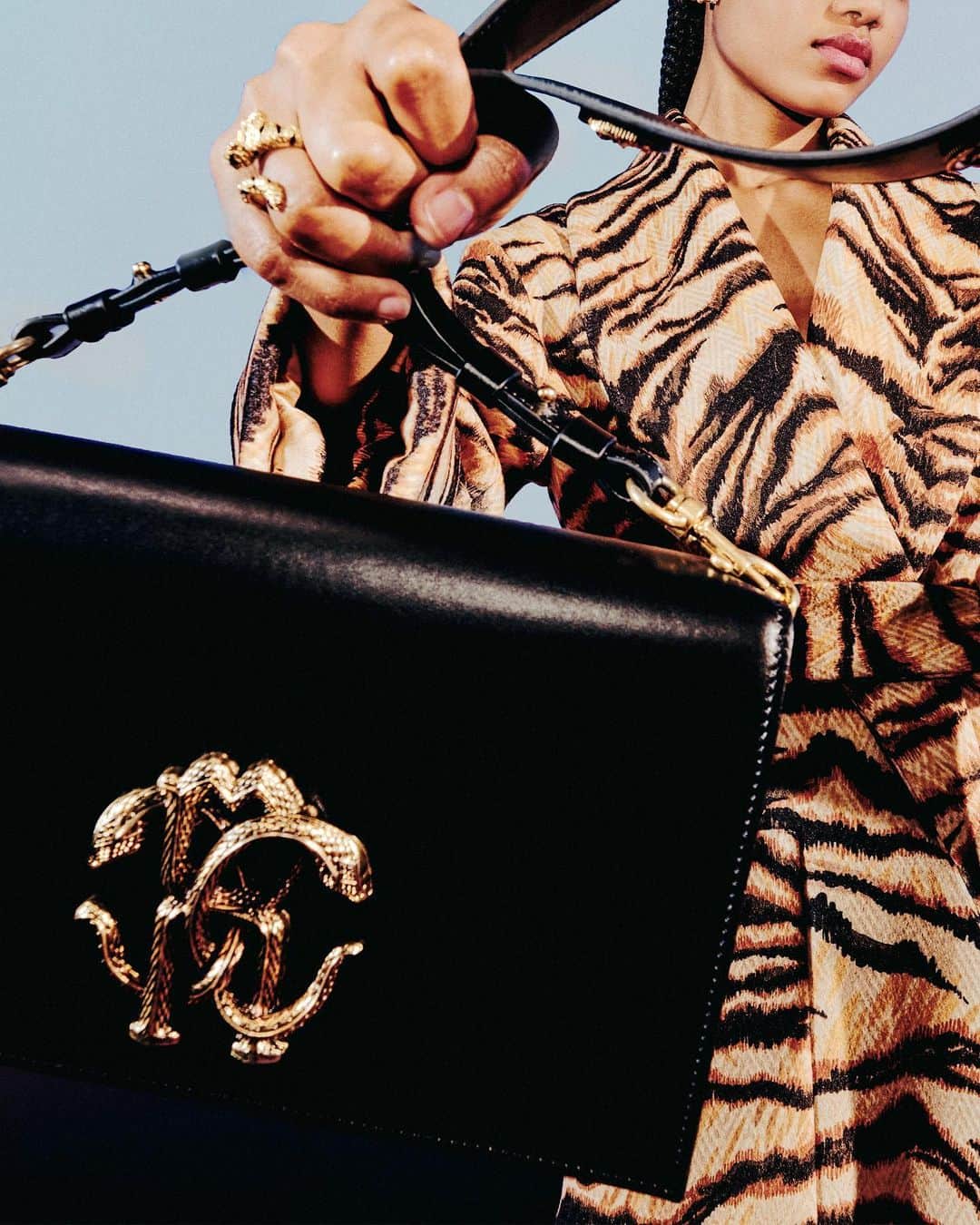 ロベルトカバリのインスタグラム：「Weekend freedom. Behold the allure of a tiger print embracing your body on Sunday strolls. Complete your look on point with the Mirror Snake black shoulder bag. It’s officially hot outside.   The #RobertoCavalliFW2324 collection awaits you at the link in bio and in all boutiques.」