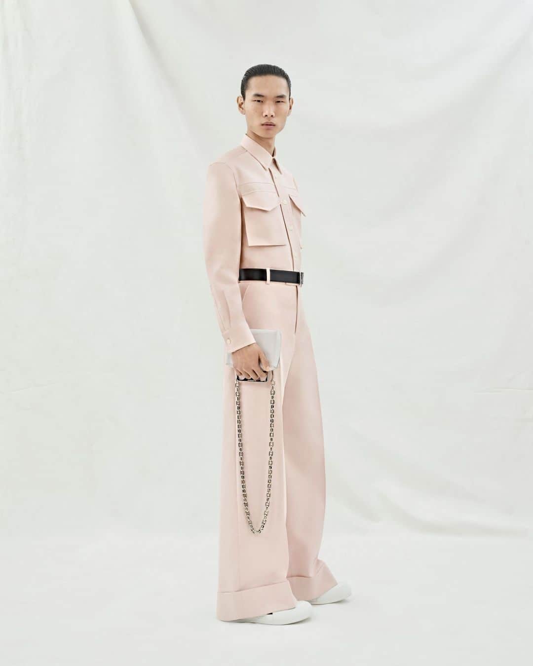 アレキサンダー・マックイーンのインスタグラム：「A shirt with utility pockets and wide-legged trousers with turn-ups in blossom cotton, worn with a black belt and #McQueenKnuckle clutch. ⁣ ⁣ Discover #McQueenMenPreSS24 via the link in bio.⁣ ⁣ Photographed by @Jet.Swan ⁣⁣ Video by @EbbaHult ⁣⁣ Track: Indigo by Hit By A Rock⁣⁣ Music Director: John Gosling」
