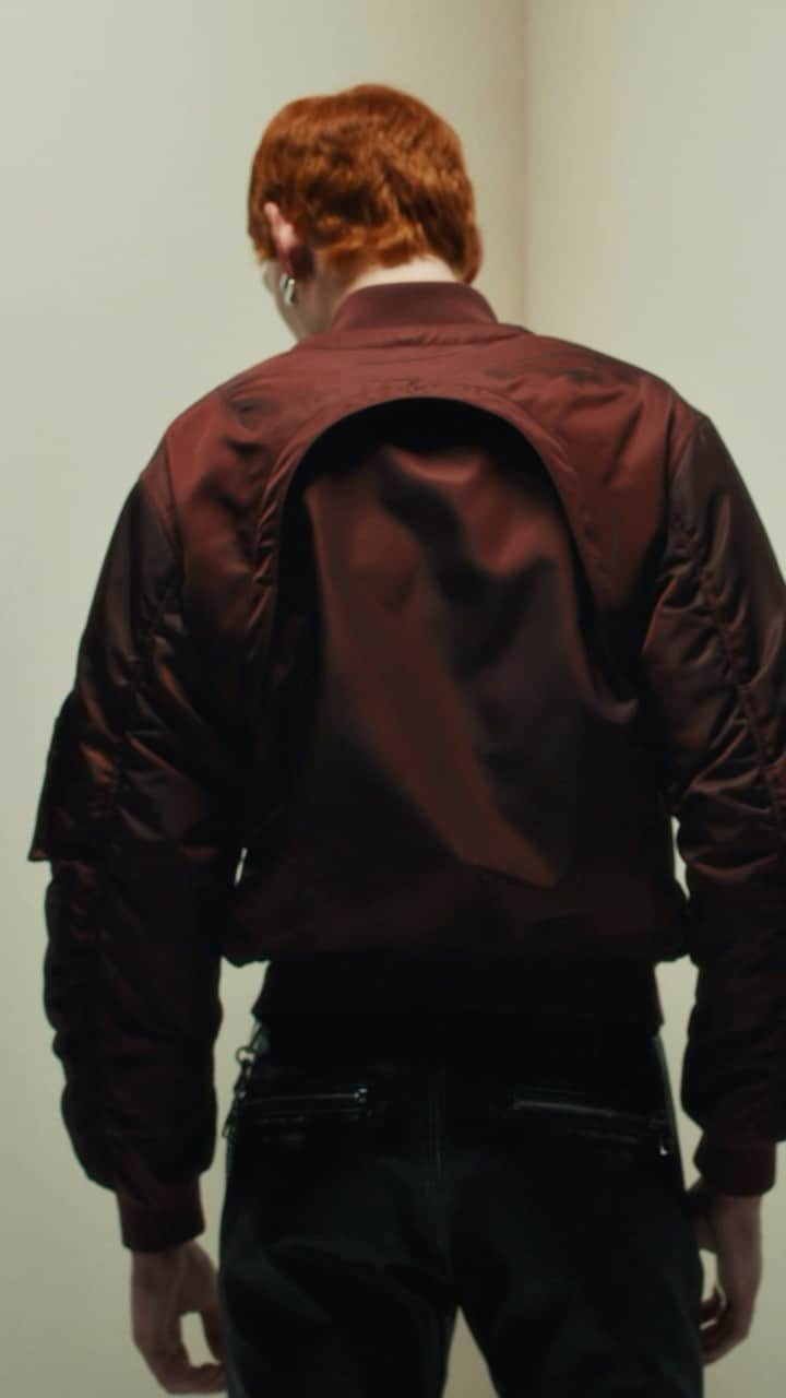 アレキサンダー・マックイーンのインスタグラム：「A #McQueenMenPreSS24 jacket with detachable harness sleeves in bordeaux nylon satin and black distressed biker trousers.  Discover the collection via the link in bio.  Video by @EbbaHult ⁣ Track: Indigo by Hit By A Rock⁣ Music Director: John Gosling」