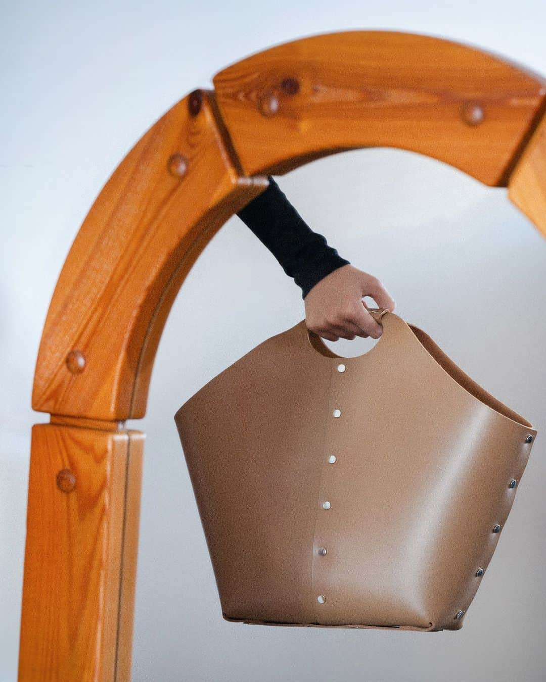 エンダースキーマのインスタグラム：「“assemble” assemble cage bag big  “assemble” is a collection of leather items that are 'assembled' and formed by riveting leather patterns, without sewing processes, like making a plastic model kit. The simple, unlined structure gives the products a more minimal look and highlights the natural color of the interior cowhide against the gloss leather exterior.  #assemble #henderscheme #2023sa」