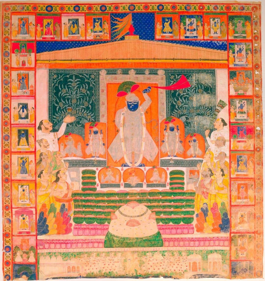 スミソニアン博物館のインスタグラム：「Each of the five days of #Diwali celebrates a different legend of good triumphing over evil.  This large-scale painting on cloth (also known as Picchwai) from Nathdwara in northern India depicts Annakut, a holiday that draws the community together in gratitude to the Hindu deity Krishna. For some calendars, this joyous occasion of generosity and abundance marks a new year at the harvest.  When the god Indra caused a devastating storm, Krishna lifted up Mount Govardhan to shelter his community. For Annakut, each community gathers to offer a mountain of fresh rice and sweet treats to Krishna ShriNathji.  In this painting, Krishna ShriNathji, or Krishna as a young boy, is in the center holding up his hand in refuge. Afterwards, food offerings return to the community as blessings, Prasad, and everyone partakes of his grace!  Image: Nathadwara, Rajasthan state, India, Late 19th Cen., Opaque Watercolor on Cotton, 188.9 x 177.8 cm, National Museum of Asian Art, Smithsonian Institution, Gift of Karl B. Mann, S1992.36  Within a shrine that resembles a grand house stands a resplendent ShriNathji in silver with garlands of flowers. He is surrounded by seven other forms of Krishna. On either side of the shrine stand priests, one holding an aarti flame in blessing. Devotees wearing opulent textiles gather before the shrine. A mountain of food fills the foreground: rice decorated with dried fruits, baskets presenting the textures of chappan bhog, fifty-six distinct food offerings collectively offered by the community. A border has vignettes of ShriNathji celebrated throughout the year, below, decorated cows frolic as part of the Annakut celebration.」