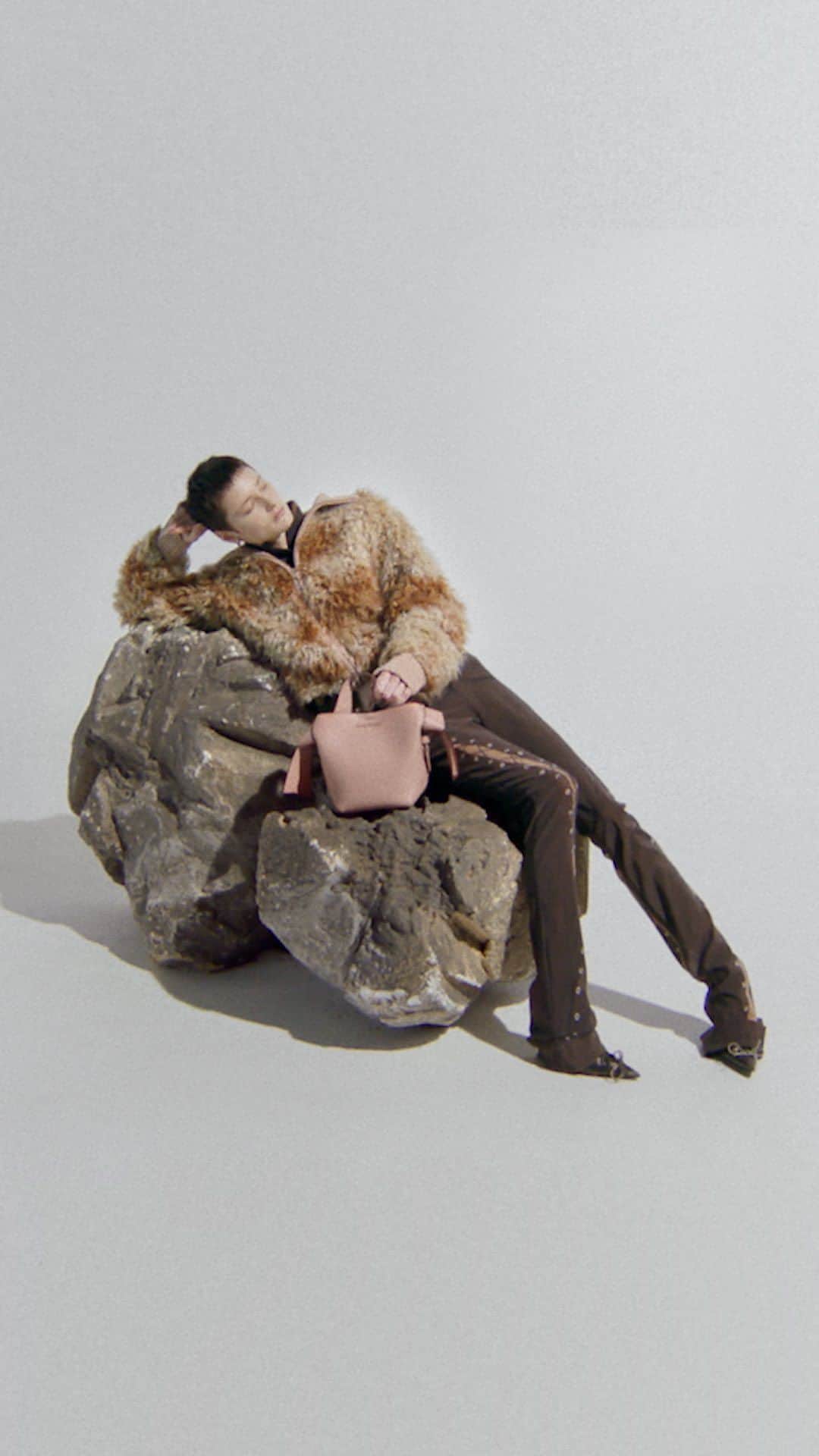 のインスタグラム：「Cosying up in FW23. Discover fluffy outerwear and the #Musubi bag in Acne Studios pink, available now.   Photographer: @EstelleHanania Stylist: @Leopolda.Duchemin Hair: @TomWrightHair Make-Up: @Masae__Ito Set Design: #AliceKirkpatrick (@Alicekpk)  Casting: @JuliaLangeCasting Nails: @ElsaDurrens」