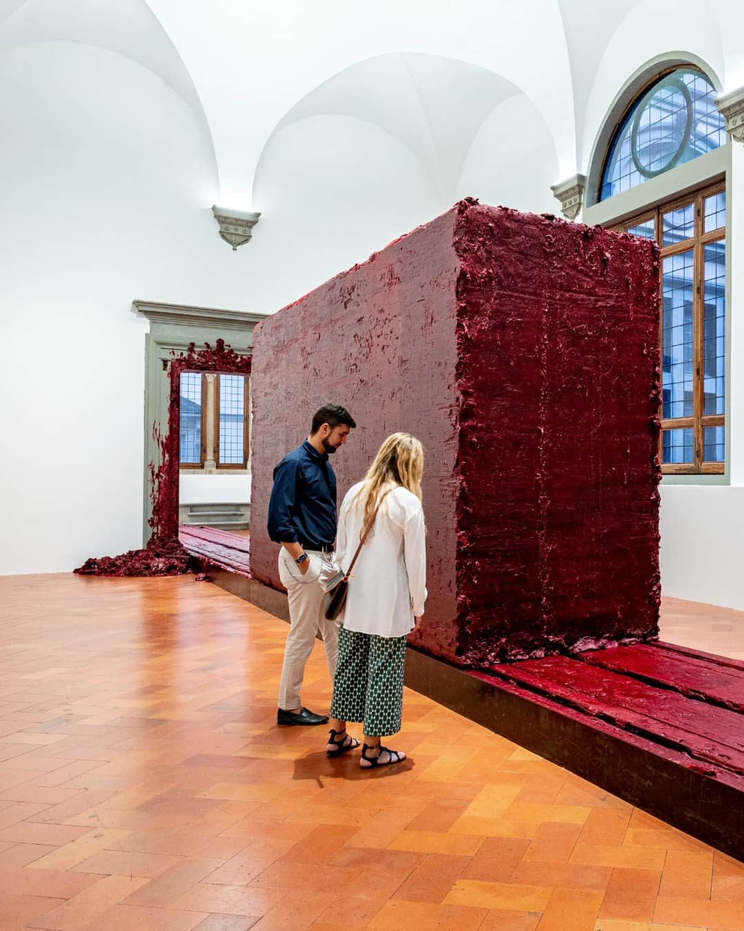 パラッツォストロッツィさんのインスタグラム写真 - (パラッツォストロッツィInstagram)「Tra le opere di Anish Kapoor più affascinanti esposte a Palazzo Strozzi troviamo senza dubbio “Svayambhu”. Il titolo dell’opera deriva dal sanscrito e si riferisce a ciò che si è creato da sé, a ciò che si è "autogenerato”. Un monumentale blocco di cera rossa si plasma passando tra le due sale del Palazzo, lungo un binario di quasi venti metri, con un movimento lentissimo e quasi impercettibile della durata di un’ora tra andata e ritorno. La materia avanza e, ai nostri occhi, sembra che una forza la schiacci, spingendola a oltrepassare la porta e lasciando su di essa tracce rosse del suo passaggio forzato. Un'esperienza straordinaria di nascita, morte e violenza si svela nel lento movimento di questo imponente lavoro di Anish Kapoor.  #AnishKapoor #UntrueUnreal ti aspetta fino al 4 febbraio 2024 tutti i giorni, festivi inclusi, dalle 10.00 alle 20.00 e i giovedì fino alle 23.00. Scopri di più sulla mostra e acquista il tuo biglietto al link: https://ow.ly/9bh950Q7883 _ Among Anish Kapoor's most fascinating works exhibited at Palazzo Strozzi we find "Svayambhu." The artwork's title comes from Sanskrit and refers to that which "self-generated." A monumental block of red wax is molded as it passes between the two rooms of the Palazzo, along a track of almost twenty meters, in a very slow and nearly imperceptible movement lasting an hour. The matter advances and it seems like a force pushes it through the door, leaving red traces of its forced passage. An extraordinary experience of birth, death and violence is revealed in the slow movement of this impressive work by Anish Kapoor.  “Anish Kapoor. Untrue Unreal” awaits you until 4 February 2024 daily, including holidays, from 10.00 to 20.00 and Thursdays until 23.00. _ Crediti: “Anish Kapoor. Untrue Unreal”, Palazzo Strozzi, Firenze, 2023. Photo: Photo Ela Bialkowska, OKNOstudio © Anish Kapoor. All rights reserved SIAE, 2023  #PalazzoStrozzi #Firenze #Florence #ContemporaryArt」11月14日 3時55分 - palazzostrozzi