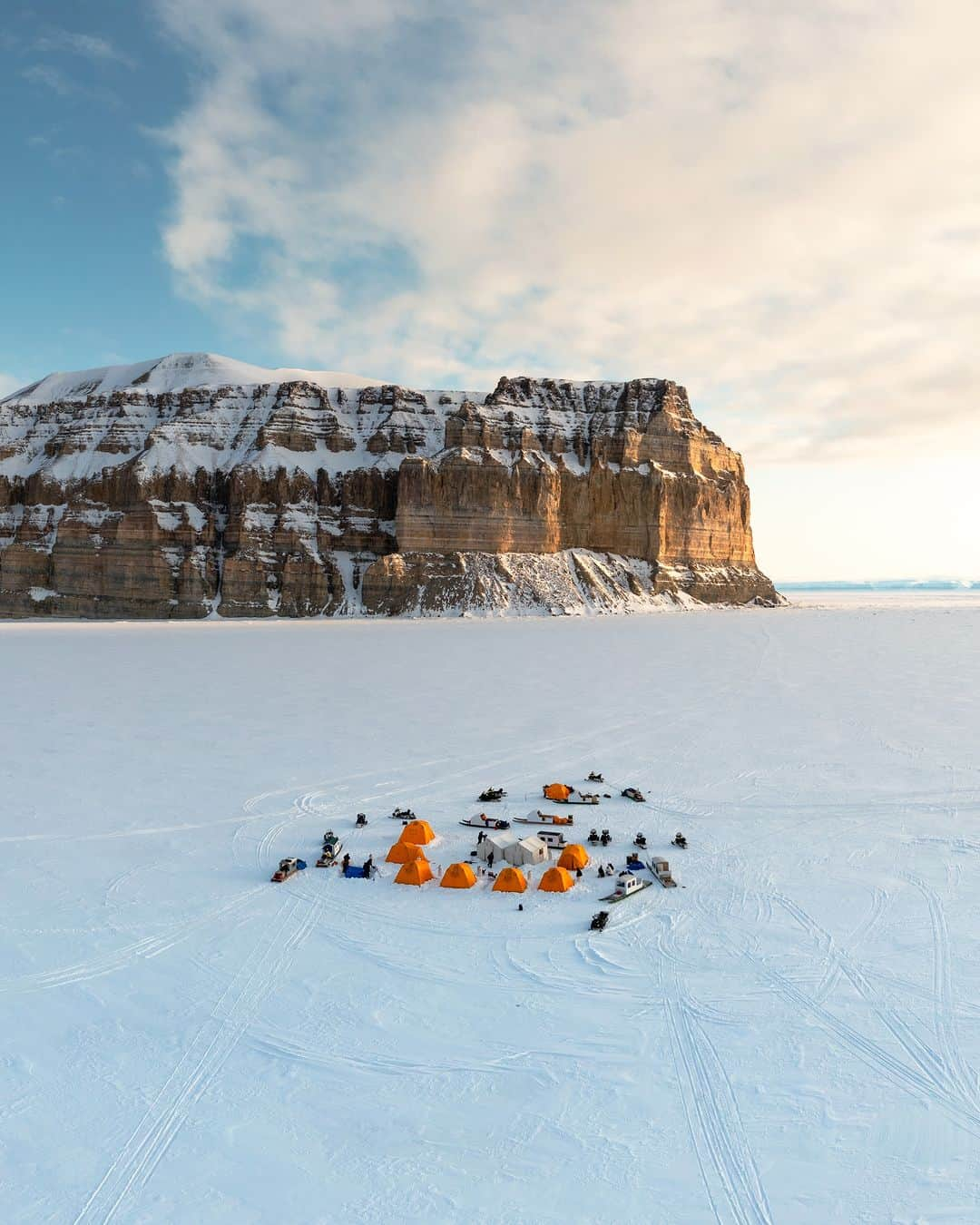 Explore Canadaさんのインスタグラム写真 - (Explore CanadaInstagram)「“For someone who is rarely home, I always search for it when I travel. Home is a feeling. It can be the warm embrace in a quaint village or as fleeting as a conversation in a local store. But perhaps the most special of these moments for me has been in Arctic Bay, Nunavut. Where local guides became good friends, where I serendipitously photographed my first wedding and got to meet with the honorable elder, Qapik in her summer cabin for a chat – reminding me so much of my time with my own grandma.  A heartfelt welcome and friendly hospitality is indicative of being Canadian and can be found across our beautifully diverse landscape – making home feel not so far away, even at the far reaches of the Arctic.” @jdubcaptures  📷: @jdubcaptures  📍 : Nunavut @destinationnunavut  #ExploreCanada #ExploreCanadaCreator #SpiritoftheArctic  Photo description:  Photo 1) Aerial view of buildings, snowmobiles and tents in a vast snowy area. In the background, there are snow capped mountains. Photo 2) Person sitting on a bed looking at their camera. Winter jackets hang above her and a pair of snow boots are at the front of the bed. Photo 3) Iceberg floating in a body of water. In the distance, there’s a boat and mountains. Clouds are in the sky. Photo 4) Wide shot of a mountain, in the distance there is a body of water and a person facing it. Photo 5) Red rocky mountain with a waterfall running through it. Photo 6) Person sitting on a bed holding the hand of a child, whose back is towards the camera. Beside the bed is a nightstand with a clock, eye glasses and a bottle of water.」11月15日 2時30分 - explorecanada