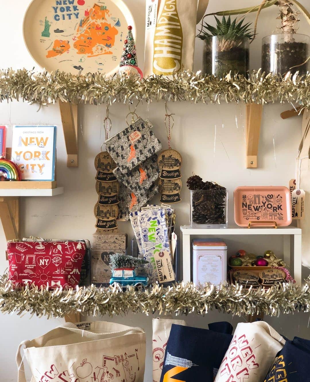 マップトートのインスタグラム：「Unwrap success this holiday season with our merchandising tips! 🎄🎁 From eye-catching festive garlands to our wide array of product choices, we've got some tips to sleigh your store's holiday sales! ✨ ⁠ ⁠ Holiday Merchandising Tips for Retailers:⁠ ⁠ - Use hooks to hang ornaments wine totes, and pouches for a playful and versatile display.⁠ ⁠ - Make sure baskets are full of product for customers to look through⁠!⁠ ⁠ - Individually roll up totes and place them in a basket or cubby⁠. Have one open as an example⁠ ⁠ - Clear vessels or trays are great for displaying small objects like holiday ornaments.⁠ ⁠ - Merchandise goods that complement each other like coffee and mugs. This inspires your customers to purchase things together, and create fun unforgettable gifts!」