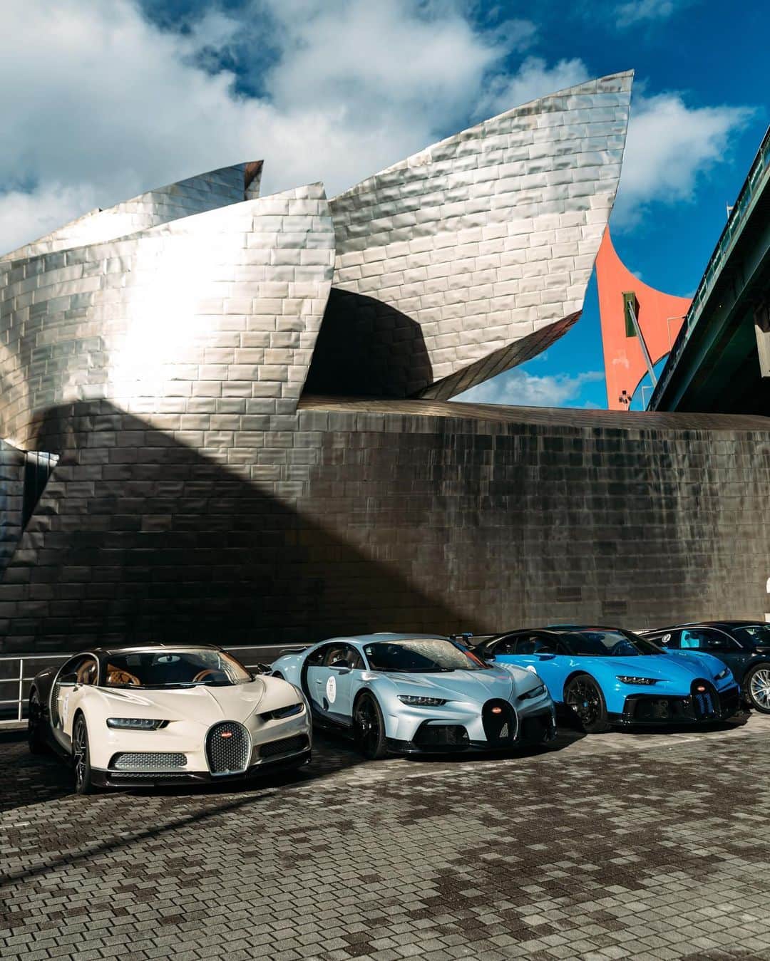 ブガッティのインスタグラム：「Guided by the coastal roads of the Bay of Biscay, the BUGATTI Grand Tour Europe 2023 by @2fast4you.it party reaches Frank Gehry’s legendary Guggenheim Museum in Bilbao, where automotive and architectural artistry beautifully collide.   The BUGATTI Grand Tour Europe 2023 guests have arrived just in time for a specially curated private experience at the museum.   #BUGATTI #BUGATTIGrandTour #BUGATTIGrandTourEurope – WLTP: bugatti.link/consumption」