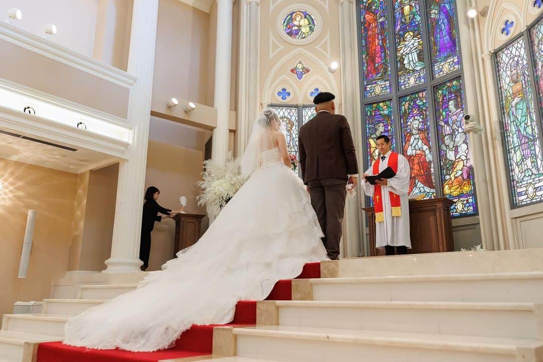 家族挙式のインスタグラム：「. 幻想的なステンドグラスの前で 誓いを立てる新郎新婦のお二人。  ロングトレーンの美しいウェディングドレスは 真っ赤なバージンロードによく映えます* . -------------------- @kazoku_wedding をフォローして、 #家族挙式 でお写真を投稿してくださいね＊* ----------------------- . “家族挙式ベスト“なら 【挙式・衣裳・美容・写真】が含まれた プランが99,000円〜叶います＊ ▽予約はTOPのリンクから❁ >>> @kazoku_wedding  ------------------- #家族挙式 #ベストアニバーサリー #家族 #Family #bestanniversary #少人数婚 #ウェディング #結婚式準備 #結婚式 #フォトウェディング #プレ花嫁 #卒花#日本中のプレ花嫁さんと繋がりたい #花嫁#卒花嫁 #国内挙式 #ウェディングドレス #プラコレ #DRESSY花嫁 #花嫁コーデ #花嫁コーディネート #花嫁衣裳 #ブライダル #チャペル #チャペル前撮り #ステンドグラス #挙式 #大人花嫁 #オリジナルウェディング」