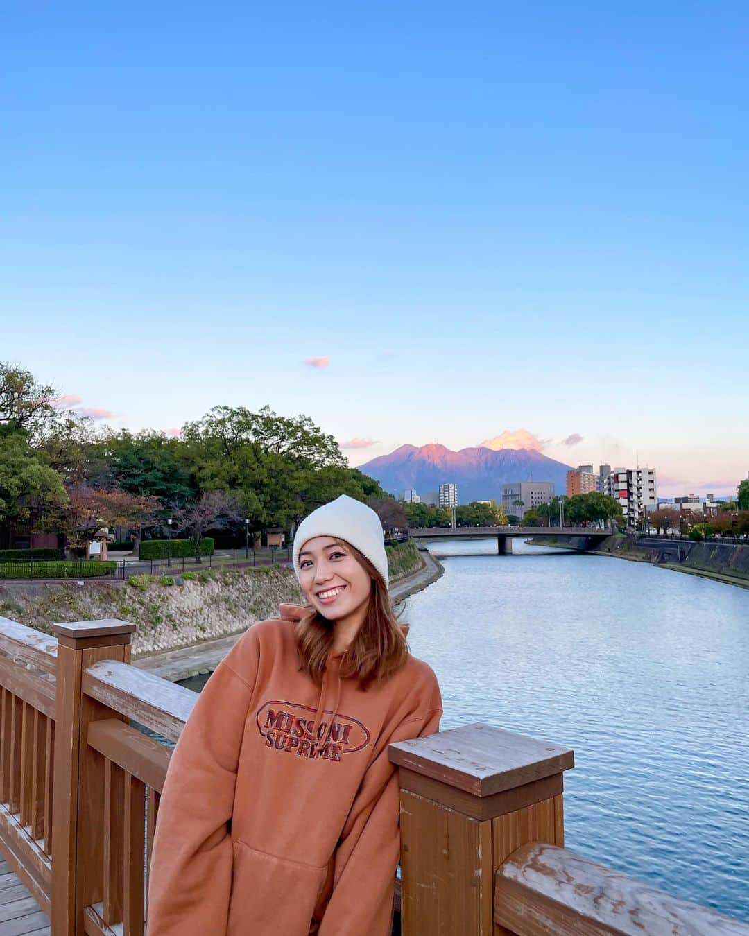 佐藤あいりさんのインスタグラム写真 - (佐藤あいりInstagram)「🍦  大学生時代に歩いていた甲突川沿いの歩道🌳 陽が沈むタイミングで 桜島がほんのりピンクオレンジ🧡  9年前がほんの少し、恋しくなりました。  この日、ちょっとだけ桜島が噴火しました🌋💭 入学1ヶ月後の朝、 起きたら空がどんどん真っ暗になって パチパチパチッと火山灰が空から降ってきて 朝からパニックになった日を思い出しました🙄 そんな日もあったなぁ。  それよりも、ソフトクリームみたいに立った ニット帽が私は気になります。。。😶🍦  #桜島 #鹿児島 #sakurajima #kagoshima」11月15日 20時52分 - satoairi101