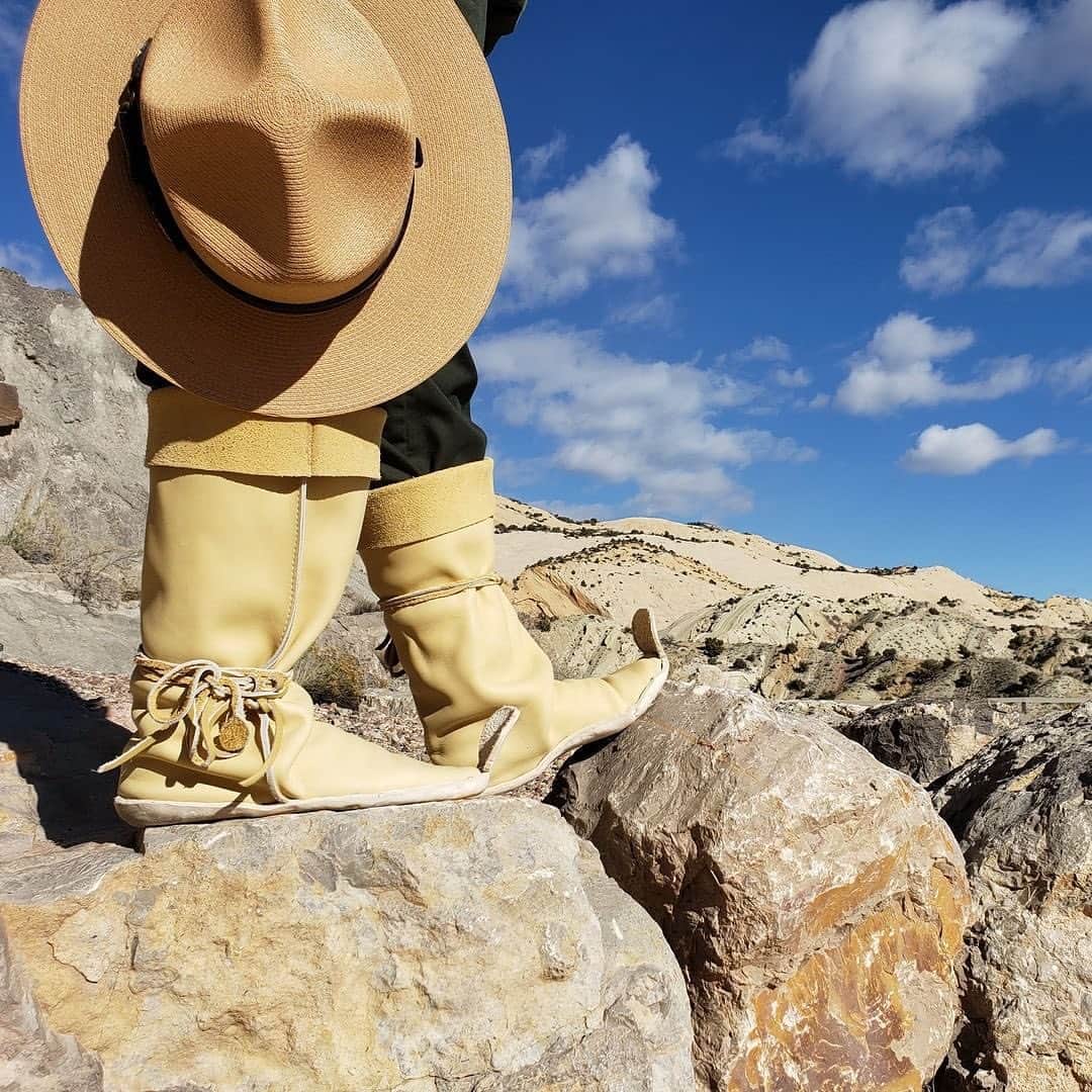 アメリカ内務省のインスタグラム：「Today is Rock Your Mocs Day — a day to celebrate Indigenous culture and the significance of moccasins.    Across the world, Native communities are wearing and sharing photos of their moccasins and honoring their Tribal individuality and heritage.    #RockYourMocs #RockYourMocsInParks #NativeAmericanHeritageMonth   Photo 1: A ranger wearing her moccasins and holding a flat hat with part of @dinosaurnps in the background.   Photo 2: A ranger wearing their moccasins inside at @lewisandclarknps.   Photo 3: Close-up of a green pant with a brown moccasin shoe on a curb at @jeanlafittenps. The moccasin has fringe and red, yellow and black beads.   Photo 4: A person wearing their Kélchí (Red Shoes) around @cedarbreaksnps.」
