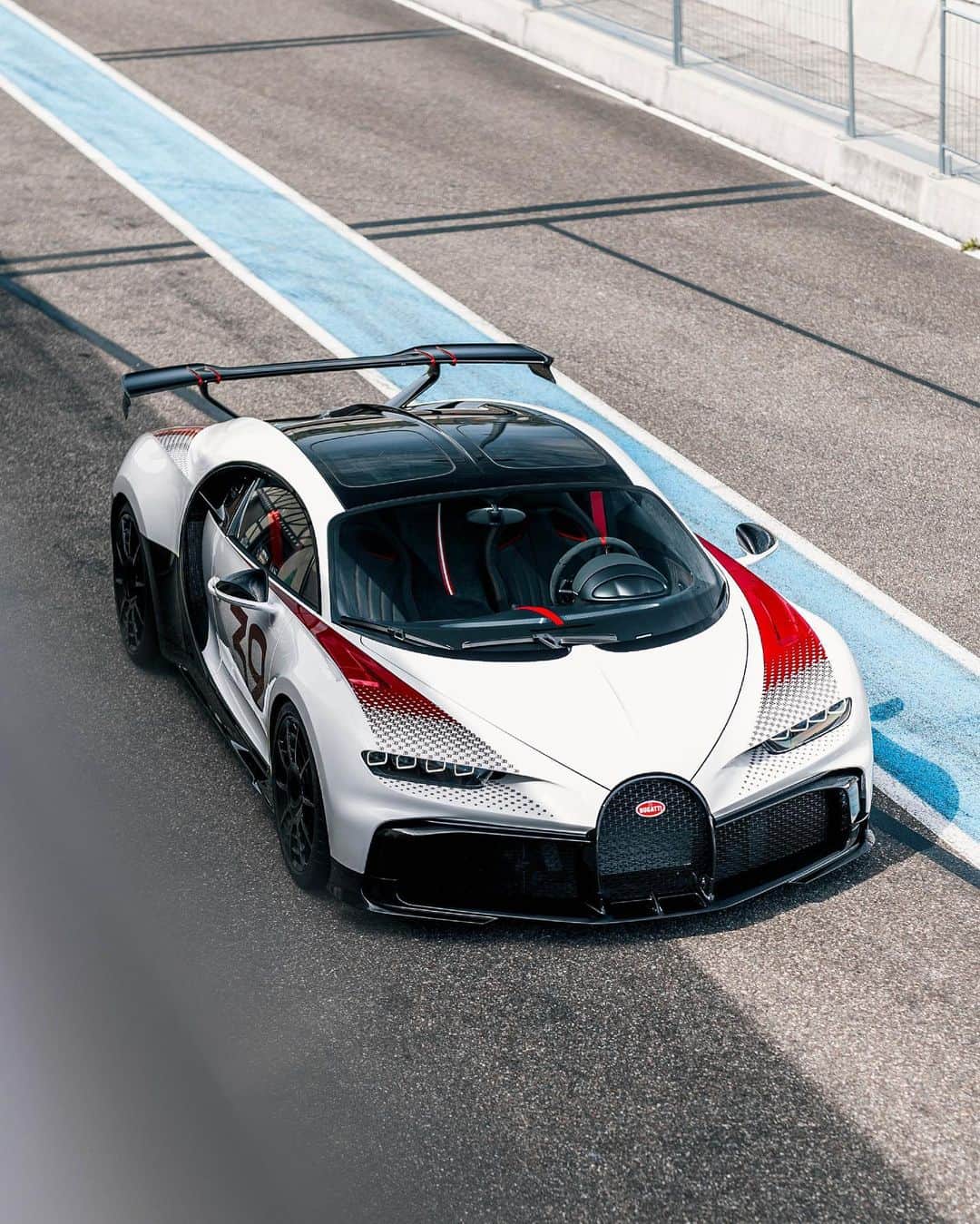 ブガッティのインスタグラム：「A ‘BUGATTI Sur Mesure’ automobile is flawlessly fusing heritage and craftsmanship with the vision of a @BUGATTISingapore client resulting in a truly personal and unique hyper sports car.  This CHIRON Pur Sport ‘Grand Prix’ is one of only two Sur Mesure vehicles with a ‘Grand Prix’ treatment – paying tribute to the marque’s historic motorsport greatness.   The exterior immersed in ‘Blanc’ mono arrangement sets the tone, the use of ‘Grand Prix Red’  for the fading ‘EB’ logo pattern on the fenders and the start number ‘32’ on the side brings to life a sense of vibrancy -  setting us back into the times of Louis Chiron’s legendary 1931 win at the French Grand Prix in a Type 51 emblazoned with the number ‘32’.  #BUGATTI #CHIRONPurSport #BUGATTISurMesure #BUGATTISingapore – WLTP: bugatti.link/consumption」