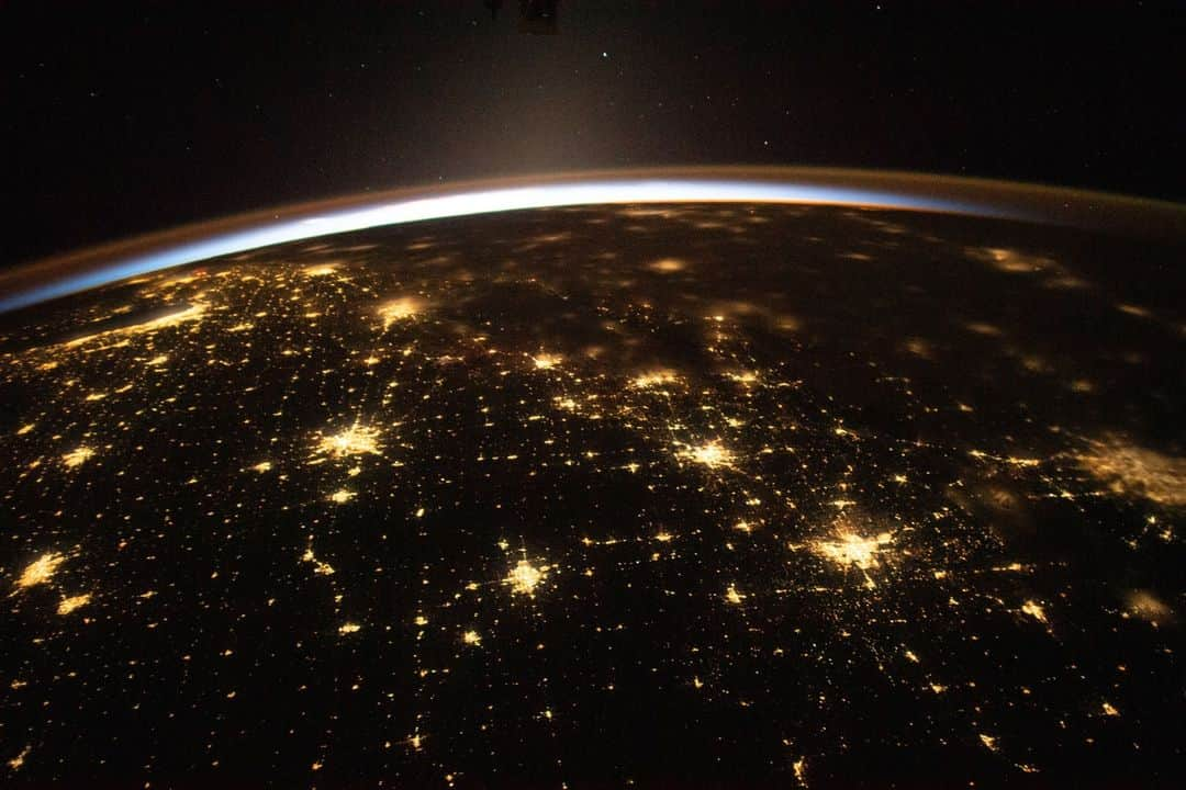 国際宇宙ステーションのインスタグラム：「The sun's first rays begin illuminating Earth's atmosphere in this photograph from the International Space Station as it orbited 260 miles above the central United States. At far left, the city lights of Chicago, Illinois, are outlined by Lake Michigan. At far right, the city lights of the Dallas/Forth Worth metropolitan area shine through the clouds.  #nasa #earth #night #city #lights #clouds #chicago #illinois #dallas #fortworth #texas」