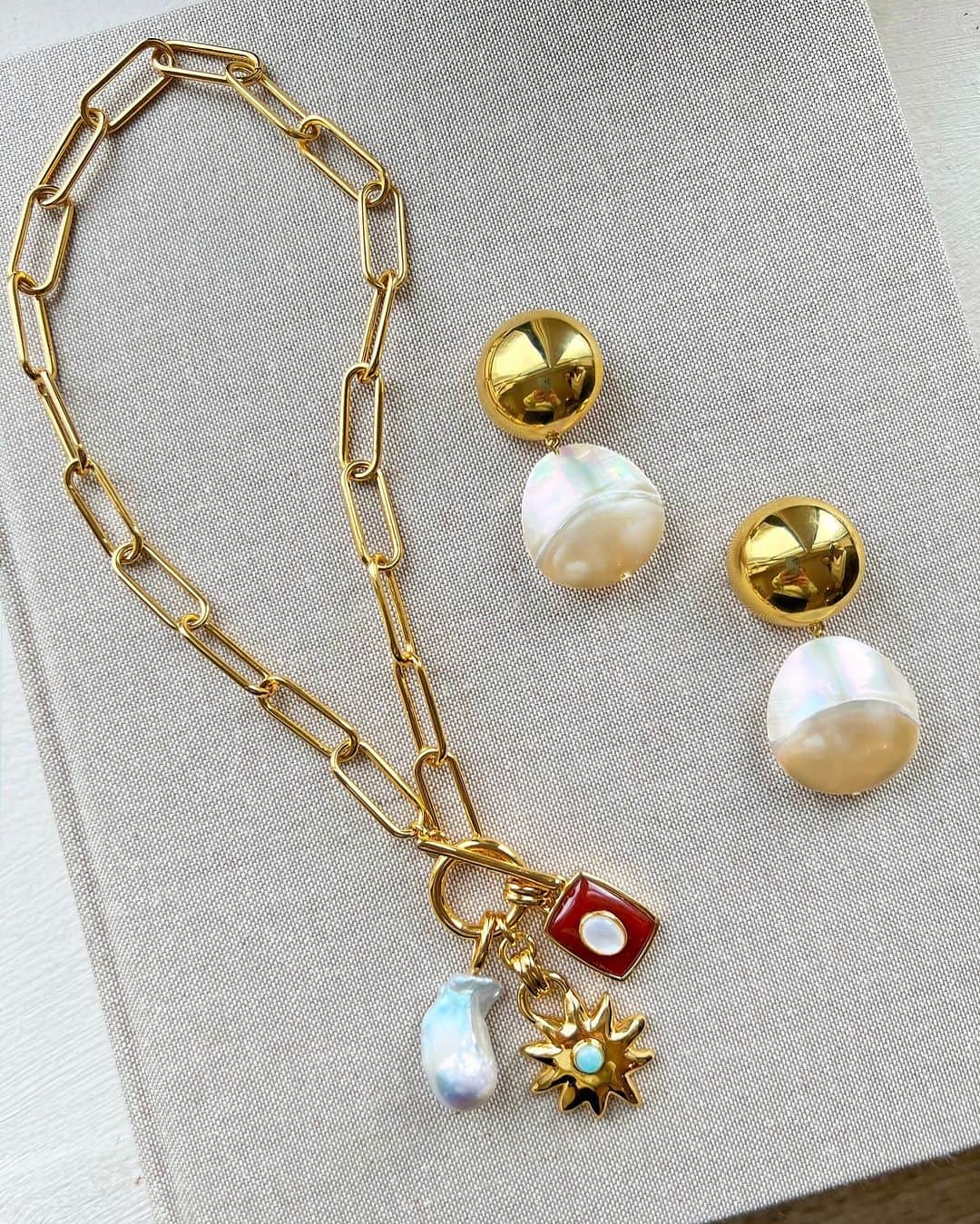 リジー フォルトゥナートのインスタグラム：「Hello, chic statement makers. This refined cluster of charms 🌟 and the coolest nautilus shell earrings 🐚 make a dreamy pair✨#lizziefortunato」