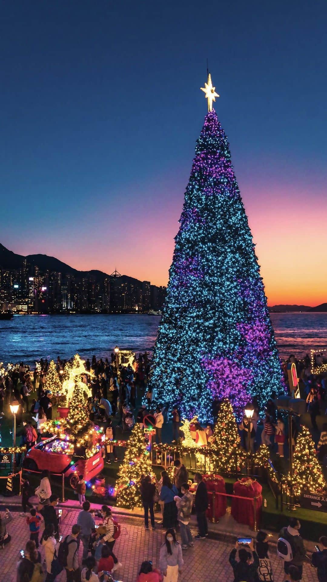 のインスタグラム：「[Mark your calendars: the giant Christmas tree is soon back🎄!] Christmas is already in the air here in Hong Kong, with tons of jolly events coming up and sparkling decorations lighting up the Victoria Harbour 🥳!   From 24 November 2023 to 1 January 2024, the annual Hong Kong WinterFest will return with the city’s tallest outdoor Christmas tree, towering over the romantic Christmas Town at the West Kowloon Cultural District waterfront. This year, the Winter Harbourfront Pyrotechnics light show will make its debut on selected dates (9, 10, 16, 17, 23, 24, 25 and 26 December), lighting up the Victoria Harbour with a dazzling array of colours and patterns🎆. Join us to catch the festive spirit! For event information, please visit 👉: bit.ly/49EVizF   Watch the video to experience the cheery atmosphere in Hong Kong!   【巨型聖誕樹即將返嚟🎄記得bookmark定喇】 話咁快聖誕節就又嚟啦，香港各大慶祝活動都陸續出爐！全城處處披上浪漫聖誕裝飾，每年見到尖東同中環嘅大型聖誕燈飾，都覺得成個維港特別靚同浪漫。🥳   今年11月24日至明年1月1日，年度盛事「香港繽紛冬日巡禮」再度返嚟，有冇好掛住呢棵全港最高戶外聖誕樹呢？佢即將再度閃耀西九文化區海濱聖誕小鎮，等你嚟一齊感受濃濃節日氣氛！今年嘅活動更首設全新「冬日維港水上煙火」🎆，於12月9、10、16、17、23、24、25、26日上演，令維多利亞港上空流光溢彩。活動詳情睇呢度👉：bit.ly/3FZ4a5D   一齊去片感受下過往香港嘅冬日浪漫點滴。  #Winterfest2023 #HelloHongKong #DiscoverHongKong 🎄🌟🎄🌟🎄🌟🎄🌟🎄🌟🎄🌟🎄🌟🎄🌟🎄🌟 What else can you do at night in Hong Kong?🌃 Stay tuned for our #HongKongAfter6 !👀 想知嚟緊夜晚有乜玩？🌃記得跟貼我哋嘅 #HongKongAfter6 ，更多節日盛事、玩樂好去處等緊你！👀」