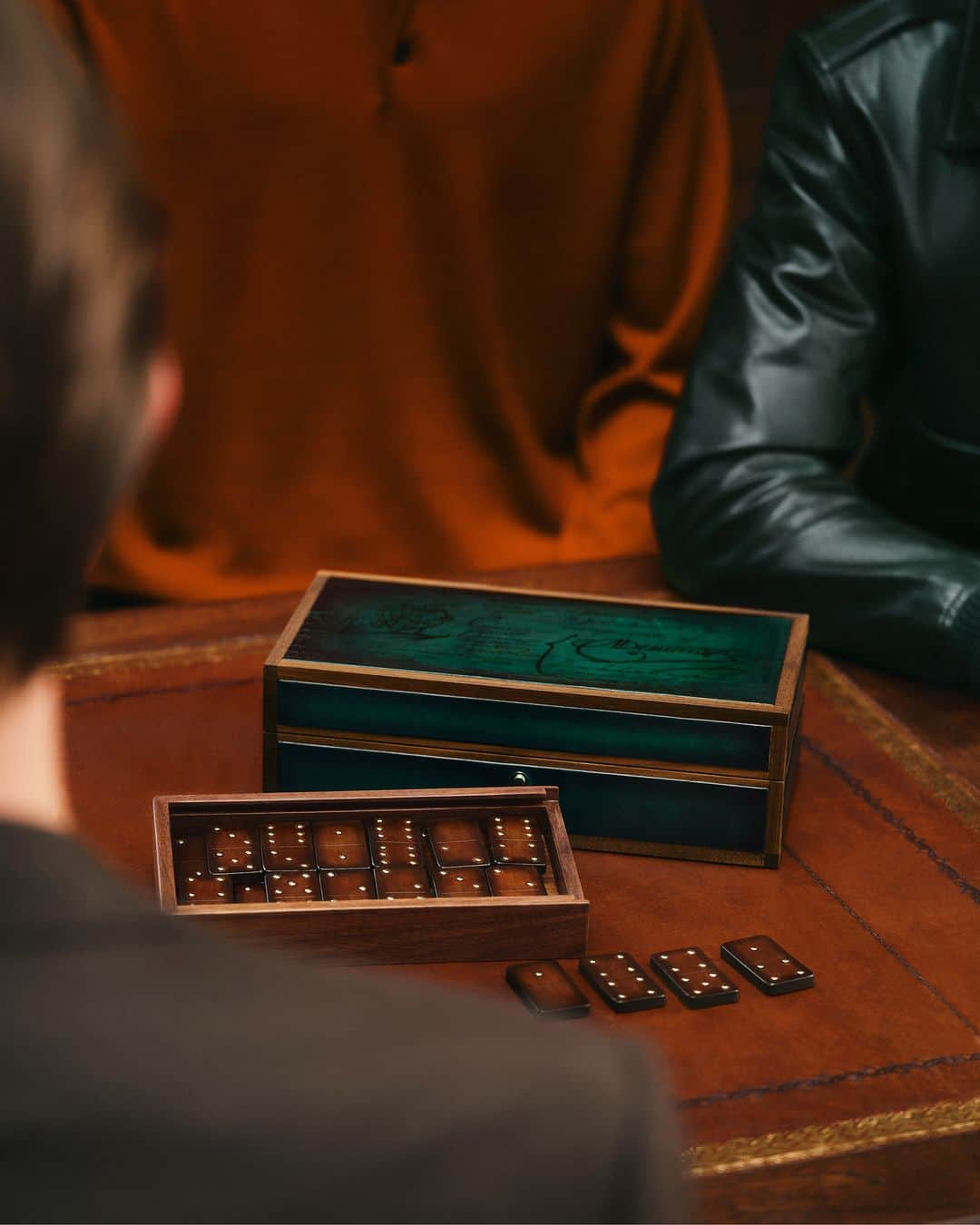 ベルルッティのインスタグラム：「- HOLIDAY SCENES WITH #BERLUTI -   Just in time for the holidays, Berluti presents Les Passe-Temps, a collection of timeless, surprising objects. Deeply rooted in Berluti’s DNA, these new pieces - like this domino set made of moulded patinated Venezia leather and bright brass elements, standing next to a classic walnut wood watchbox also covered in Venezia leather, with a vibrant Opuntia green patina - are an ode to the Maison’s history, artisanal techniques and savoir-faire.  Discover our curated gift selection, now available in-store and on the e-shop.   Creative direction by @trendsandculture for Berluti Photo by @jamesharveykelly   #BERLUTIHOLIDAY #BERLUTIGIFT」