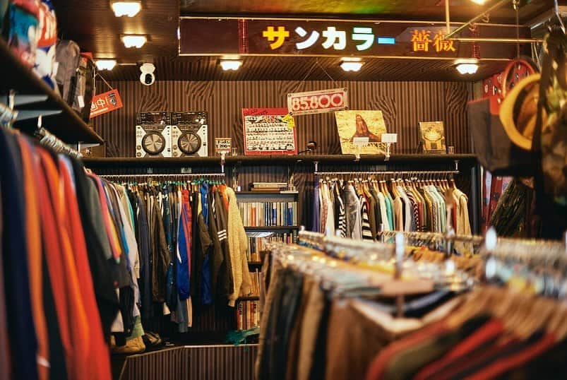 WWDジャパンさんのインスタグラム写真 - (WWDジャパンInstagram)「コラム：生成AIが接客？　東京・久我山の無人古着屋「ジャンボデンキ」  「ジャンボデンキ」と書かれた青い軒先、昭和の家電製品を広告するPOP、レトロなストライプの壁紙──今年3月に東京・久我山に誕生した「古着屋 ジャンボデンキ」は、かつて地元で愛された電気屋の外観と内装、屋号をそのまま受け継ぐ無人の古着屋だ。運営するのは、デザイン会社ザ・カンパニーの橘啓介社長。普段はファッションや建設、医療とさまざまな業種のブランディングとデザインを手掛けている。  店内には約1000点の古着が所狭しと並ぶ。客はハンガーについたタグの色で値段を判断し、料金ボックスに現金を投函。小銭がないときは、ボックス横の両替機を使う。セキュリティーは防犯カメラのみの、完全に性善説に則った店舗だが、盗難は「ほぼゼロ」というから驚きだ。「お客さんの計算違いや、金額の入れ違いによる料金のロスはある。それでも、悪意のある窃盗はない」。  橘社長が同店を始めたきっかけは、知り合いが無人古着屋を運営していたことだった。「初期費用もそれほど高くないし、自分にもできそうと安易に考えた」と笑うが、真の目的は他にある。「本業で小売店のロゴデザインやブランディングを手伝うこともあるのに、自分で店を運営していないことがずっと気がかりだった。自らの店で実績を重ねれば本業の説得力も増すし、マーケティングやシステムの実験場としても使える」。たとえ売り上げが立たなくても、やる覚悟だったのである。  ■古着屋 ジャンボデンキ 住所：東京都杉並区久我山4-50-1 営業時間：10:00～22:00（金、土、祝前日は24時間営業）  コラム全文は @wwd_jp プロフィールのリンクから  PHOTO：HIRONORI SAKUNAGA  #ジャンボデンキ#無人古着屋#古着屋#古着屋さん#古着#生成AI#久我山#kugayama#Tokyo#東京#無人販売」11月19日 12時15分 - wwd_jp