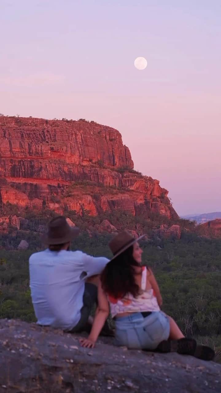 Australiaのインスタグラム：「We’ve saved you a seat at one of nature’s best shows! Welcome to the spectacular @seekakadu in @ntaustralia 🎭🤩 Our mates @betsysbiglap were lucky enough to witness this stunning moon rise at @kakadutourism’s Nawurlandja lookout. Home to the Bininj/Mungguy people, you’ll find this spot 30 minutes from #Jabiru in @ntaustralia. TIP: head to Nawurlandja for sunrise or sunset, or sit back and watch a dramatic topical summer storm roll in 🌧️   🎥: @betsysbiglap   📍: Kakadu National Park, @ntaustralia   #SeeAustralia #ComeAndSayGday #NTAustralia #TourismTopEnd  ID: A couple sits on a rocky lookout, watching the full moon rise. A rocky cliff is bathed red from the setting sun from behind the camera.」